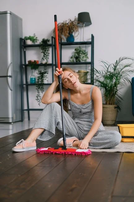 a-woman-in-a-green-shirt-and-black-gloves-vacuuming-a-gray-ottoman-5txz228u4eo